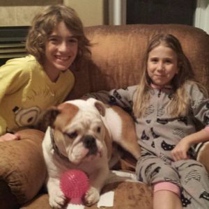 Ruger sitting with a ball and his adoptive family, two smiling young children